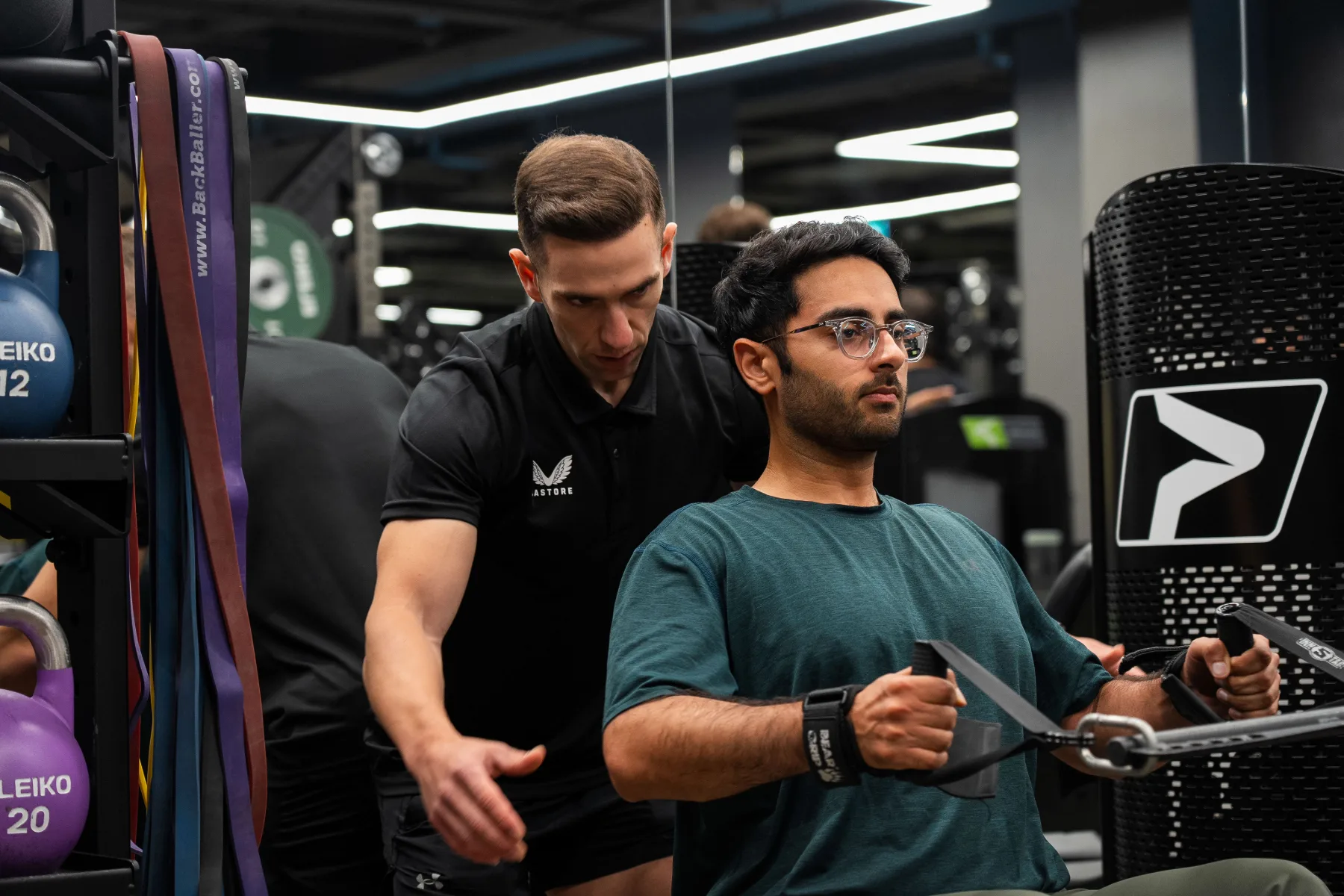 Maurizio instructing a seated client during a cable exercise in the gym