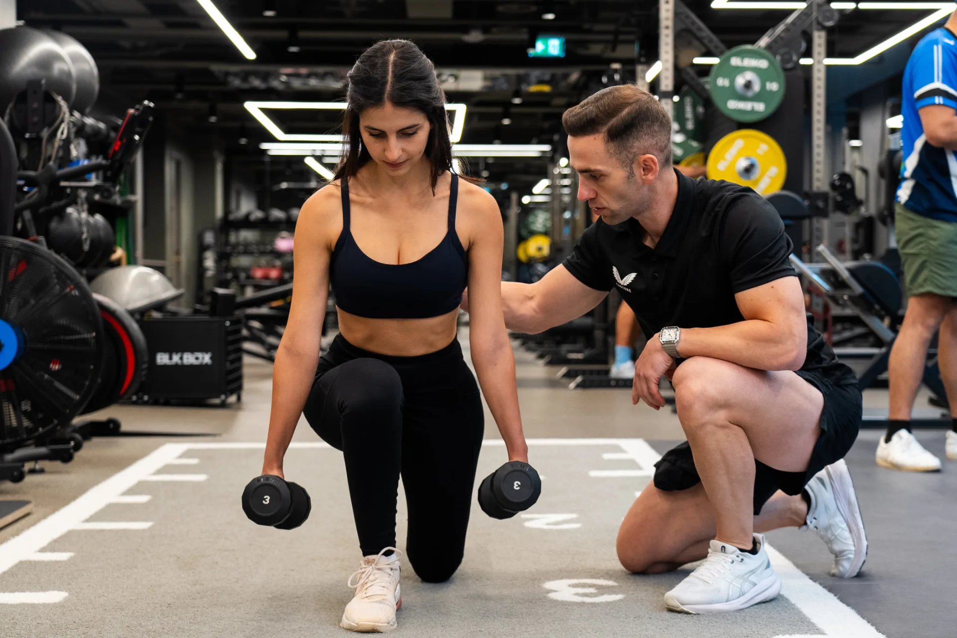 Coach guiding a client through a dumbbell lunge